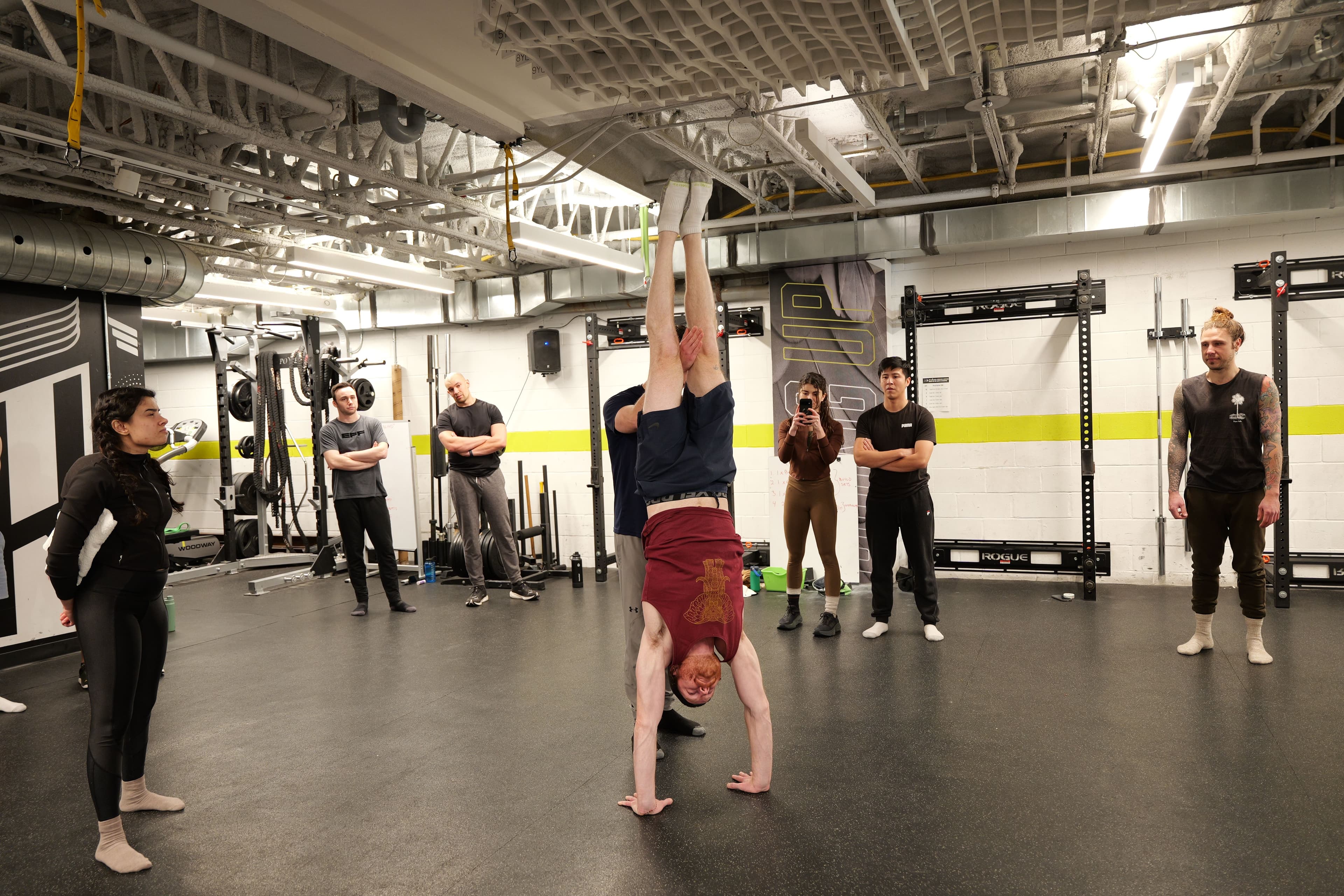 Student holding a freestanding handstand while classmates look on